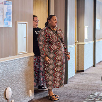 Woman in patterned robe stands in hotel hallway