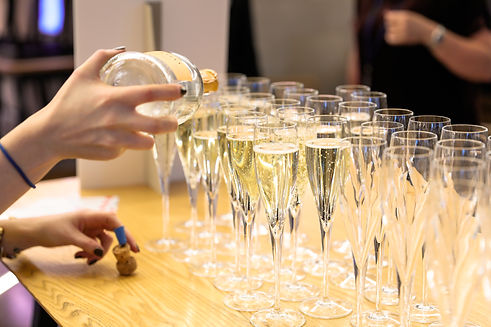 Hand pouring champagne into flutes at an event