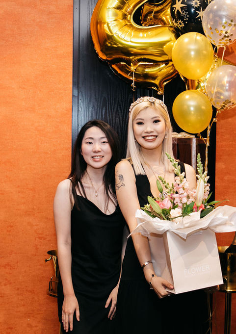 Two women celebrating birthday with balloons and flowers