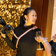 Woman holding camera, chatting with friends at event