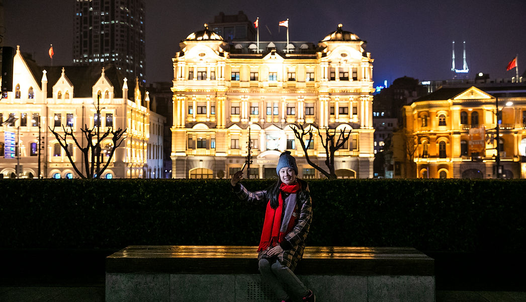 Person taking selfie, Shanghai buildings at night