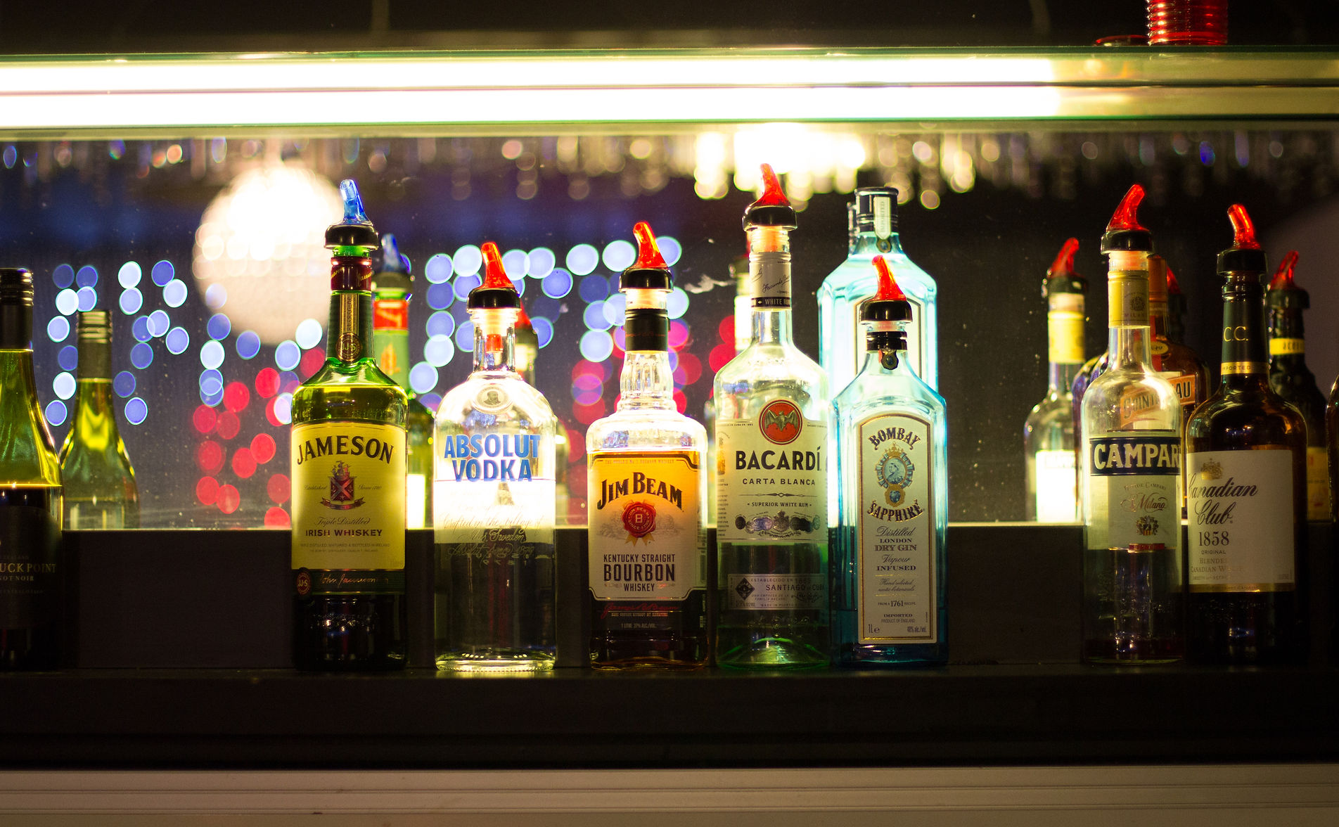 Variety of liquor bottles displayed on a backlit bar shelf