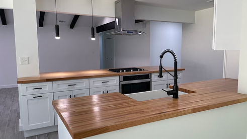 Modern custom home kitchen in Rollingwood, TX with white cabinets, wood countertops, and black fixtures.