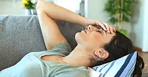 Woman sitting on bed looking exhausted from chronic fatigue and low energy