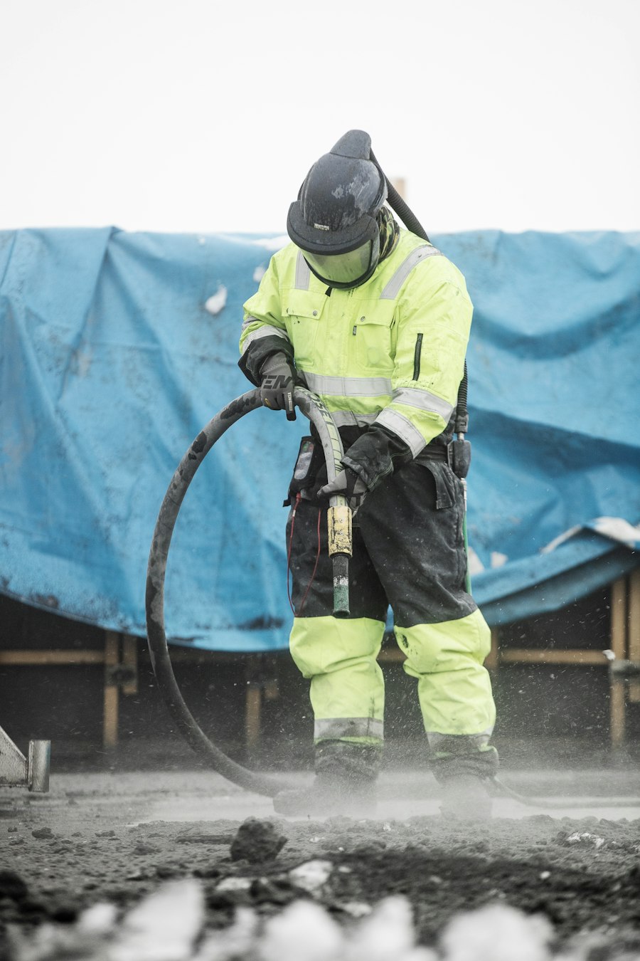 Worker in a blast suit preparing a surface