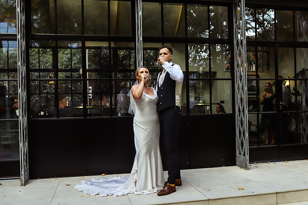 Newlyweds toast champagne in front of a window.