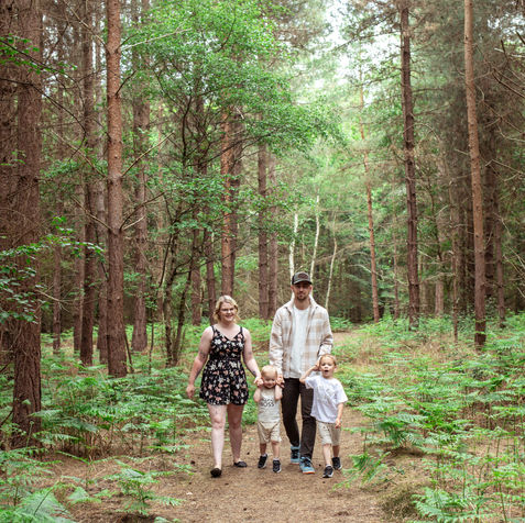 Family walking through a forest with their children.