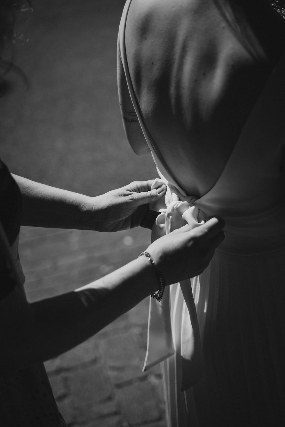 Hände binden eine Schleife am Hochzeitskleid