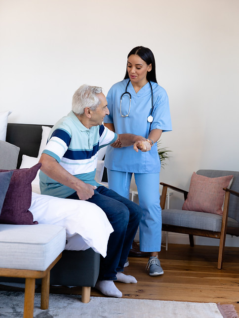 biracial-female-physiotherapist-assisting-caucasian-senior-man-getting-up-from-bed-home.jp