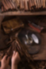 Hands making cigars from tobacco leaves