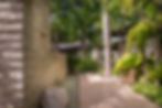 Tropical garden path, stone wall, water feature, and chair.