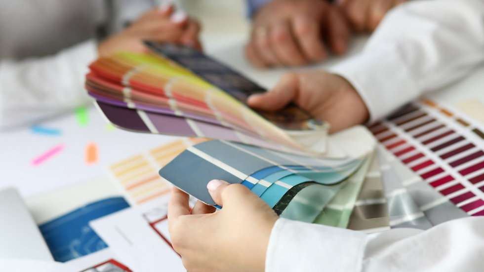 A person's hands holding up a fan deck of paint swatches.