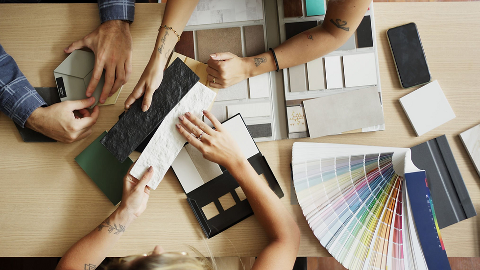 People selecting interior design materials with fabric swatches, color palettes, and sample boards on a wooden table.