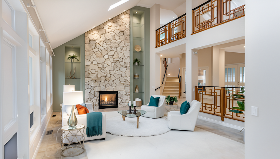 Spacious modern living room with a tall stone fireplace, white armchairs, glass coffee table, large windows, and warm natural light creating an airy aesthetic.