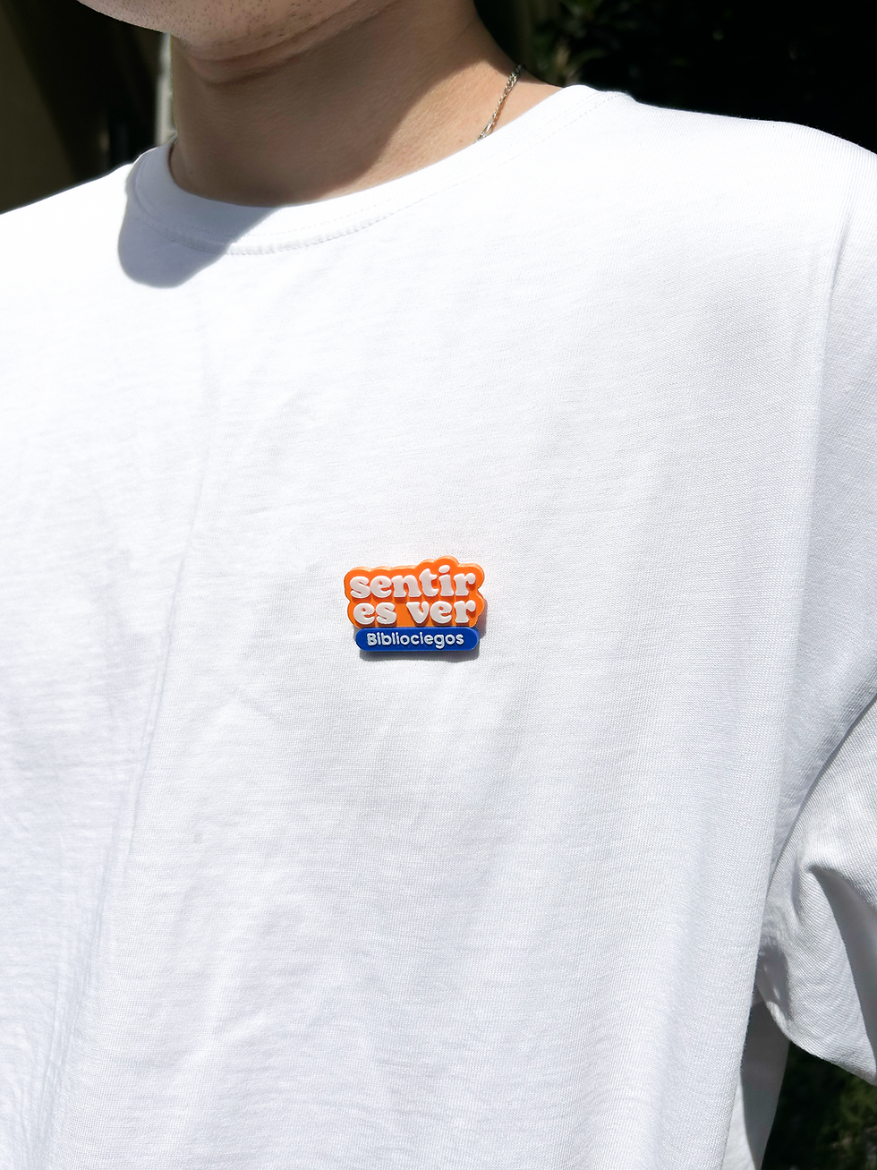 Miniatura: Fotografía de una persona con el pin "Sentir es ver" puesto en su polera.