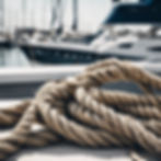 Close up photo of ropes on a boat port with water and yachts in the background, cinematic.jpg
