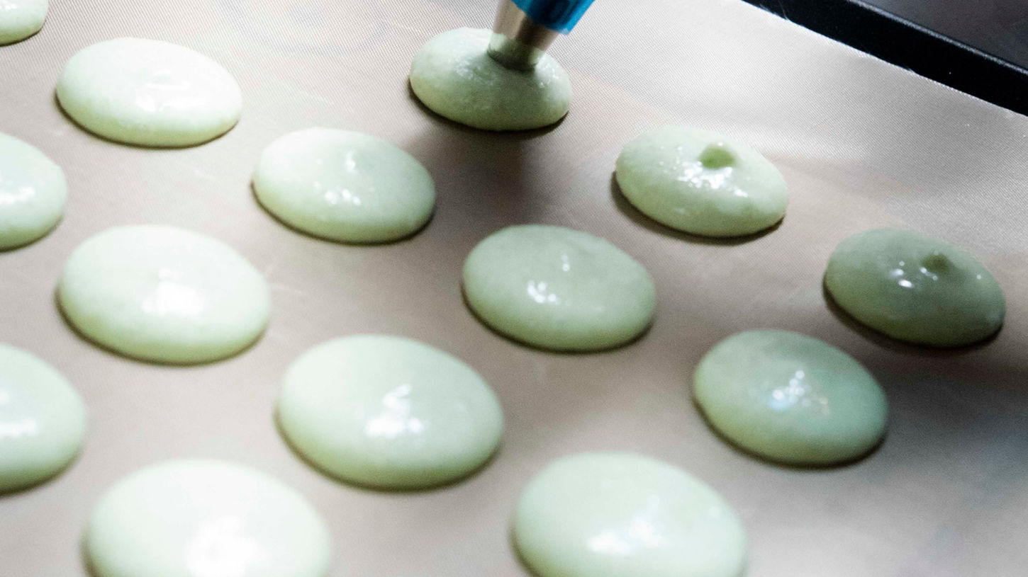 Piping macarons by hand.