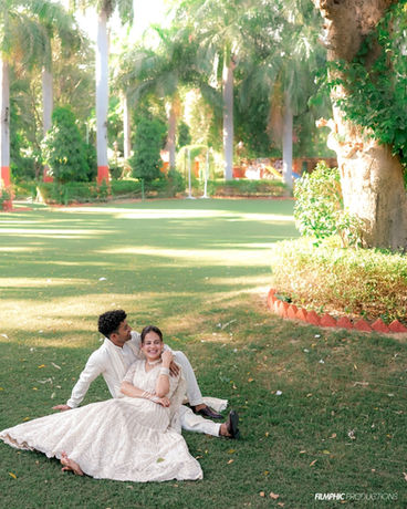 Couple sitting on grass in a garden by Filmphic Agra.