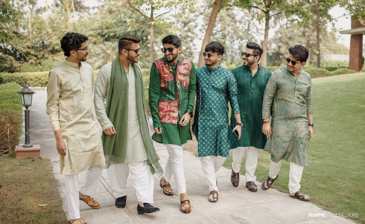 Men in ethnic wear by Filmphic Agra walking in a garden.