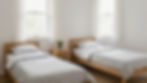 Two twin wooden beds with white bedding in a bright room.
