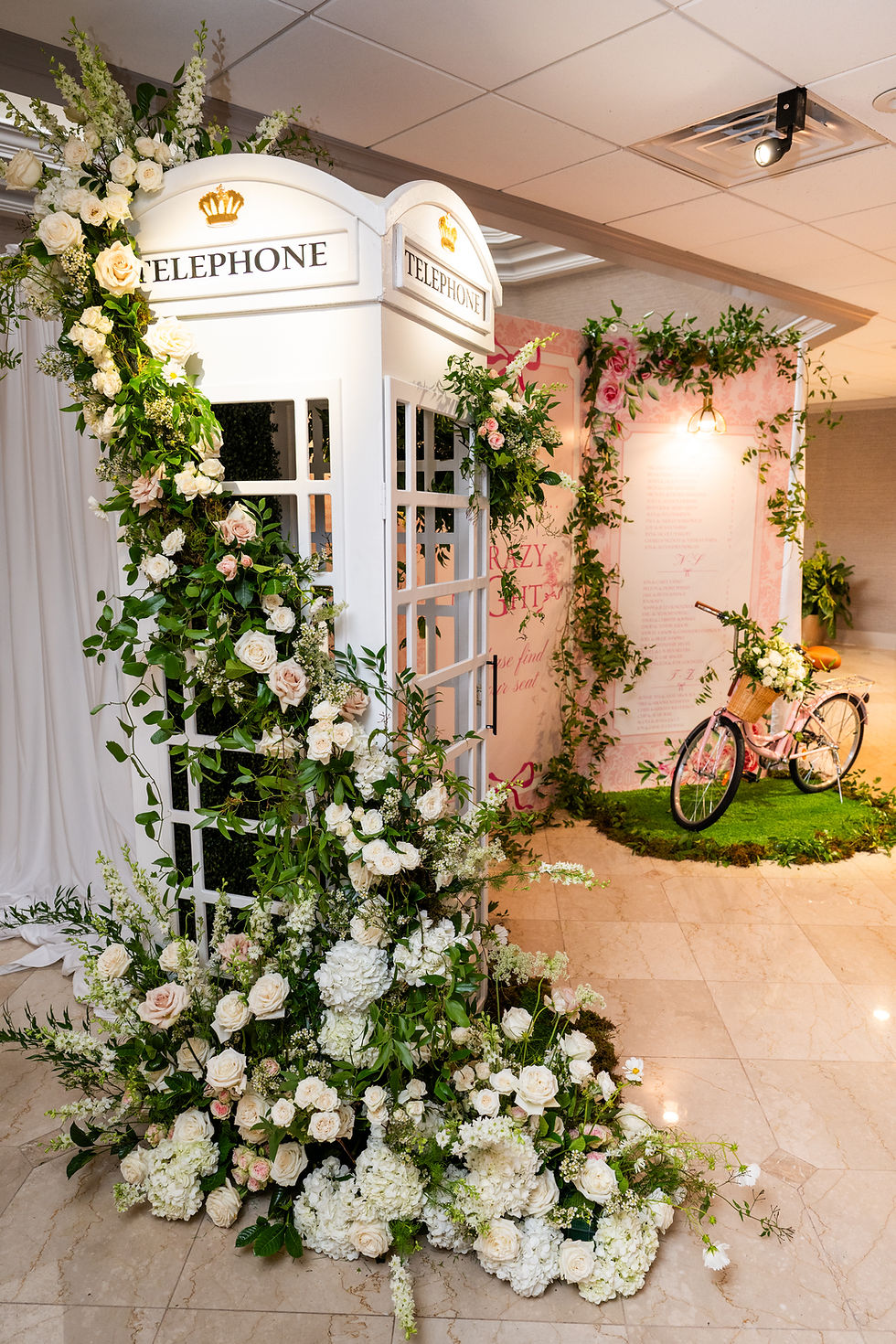 Garden-inspired event prop rentals featuring floral-covered doors, lush greenery, romantic flowers, and a decorative bicycle.