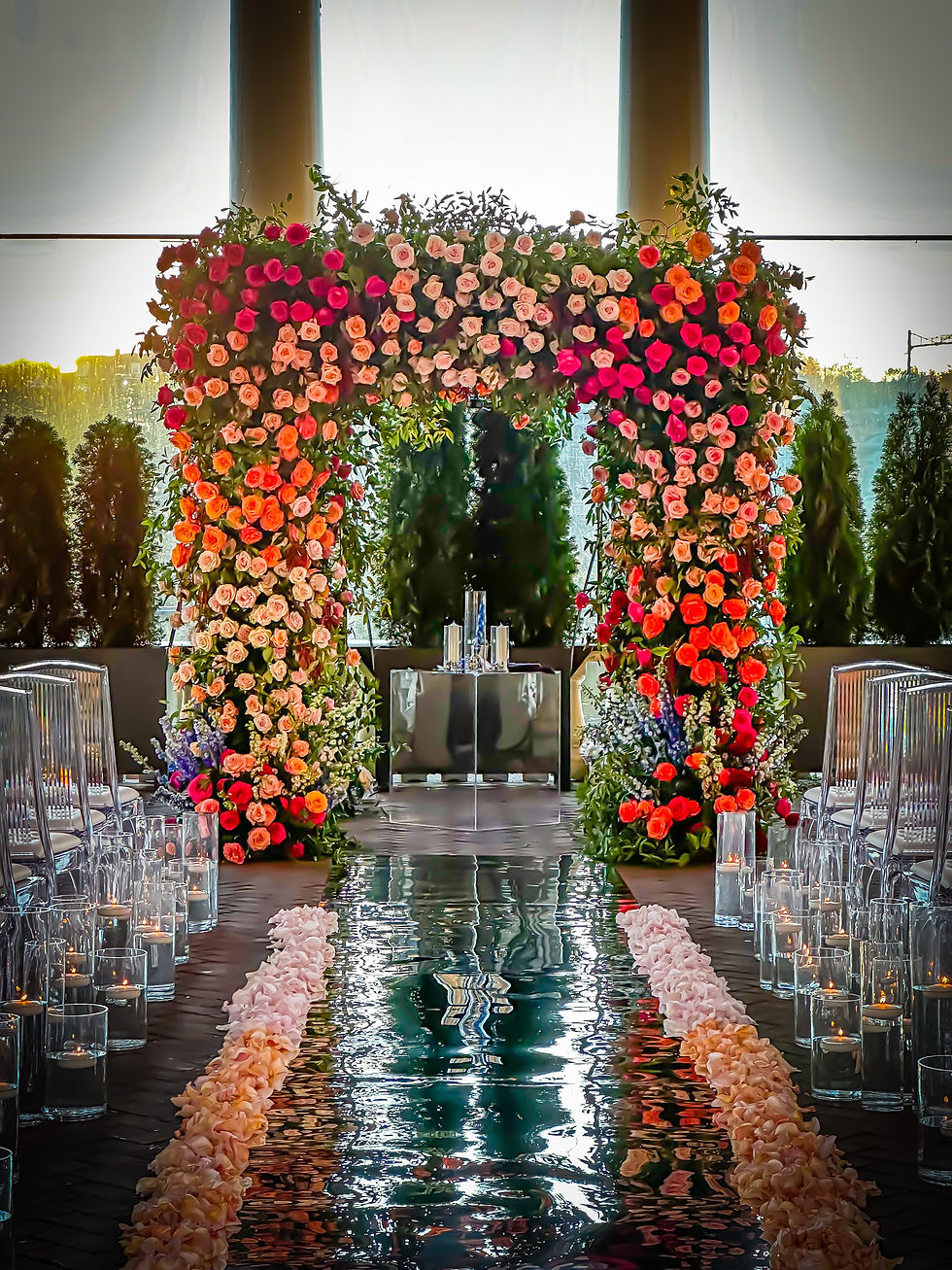 Luxury floral chuppah rental covered in vibrant red and pink flowers, creating a dramatic backdrop for an elegant ceremony.