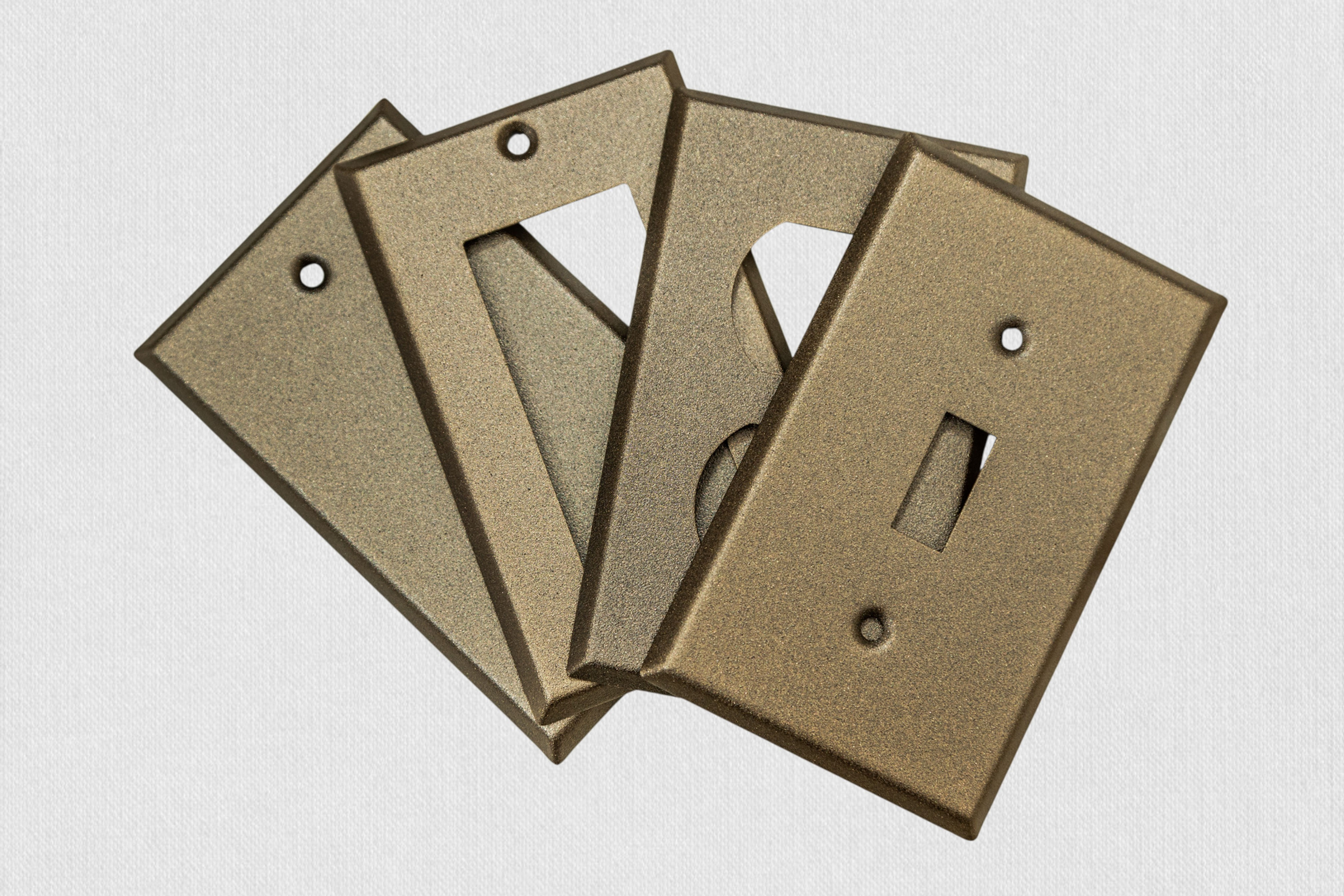 Four bronze cast switch plates on white background