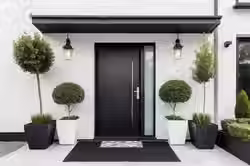 modern-black-front-door-with-potted-plants-lanterns_841778-4252