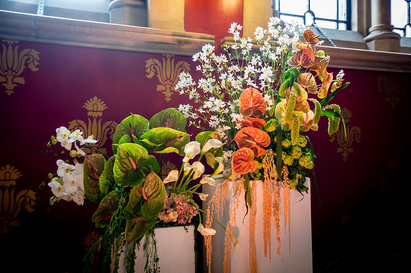 A beautiful floral arrangement featuring a mix of vibrant flowers and greenery against a richly colored wall.