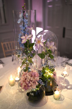 Glass cloche floral table decoration with soft candlelight