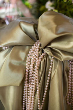 Gold satin sash with pearl string detail on a wedding chair