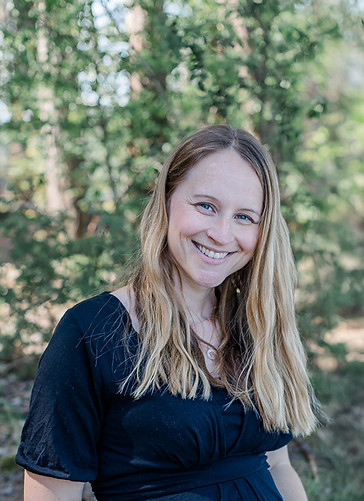 Freundliche Frau sitzt im Wald und lächelt in die Kamera