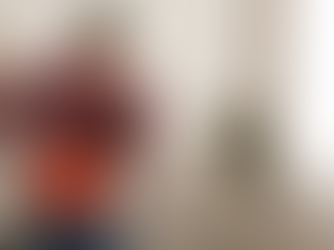 Homem de meia-idade com dor lombar provocada por hérnia discal, de pé na sala de casa, com as mãos apoiadas nas costas e expressão de desconforto.