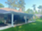 Eye-level view of a backyard patio with a wooden pergola covering and comfortable seating