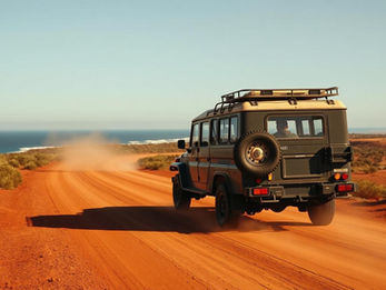 Off-road vehicle driving on a dusty desert road near the coast