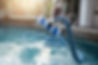 Man cleaning swimming pool with vacuum tube cleaner early in the morning.jpg