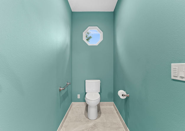 Primary bathroom with large format tile flooring, new toilet, and Andersen window.