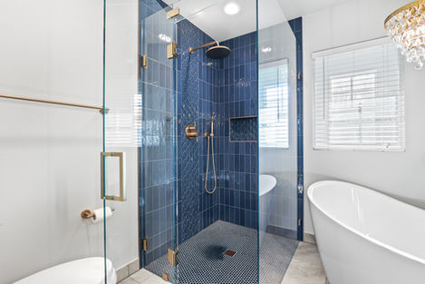 Luxury bathroom remodel in Beaverton, OR featuring a freestanding soaking tub, and a walk-in shower with dark blue tile, frameless shower glass brass hardware.
