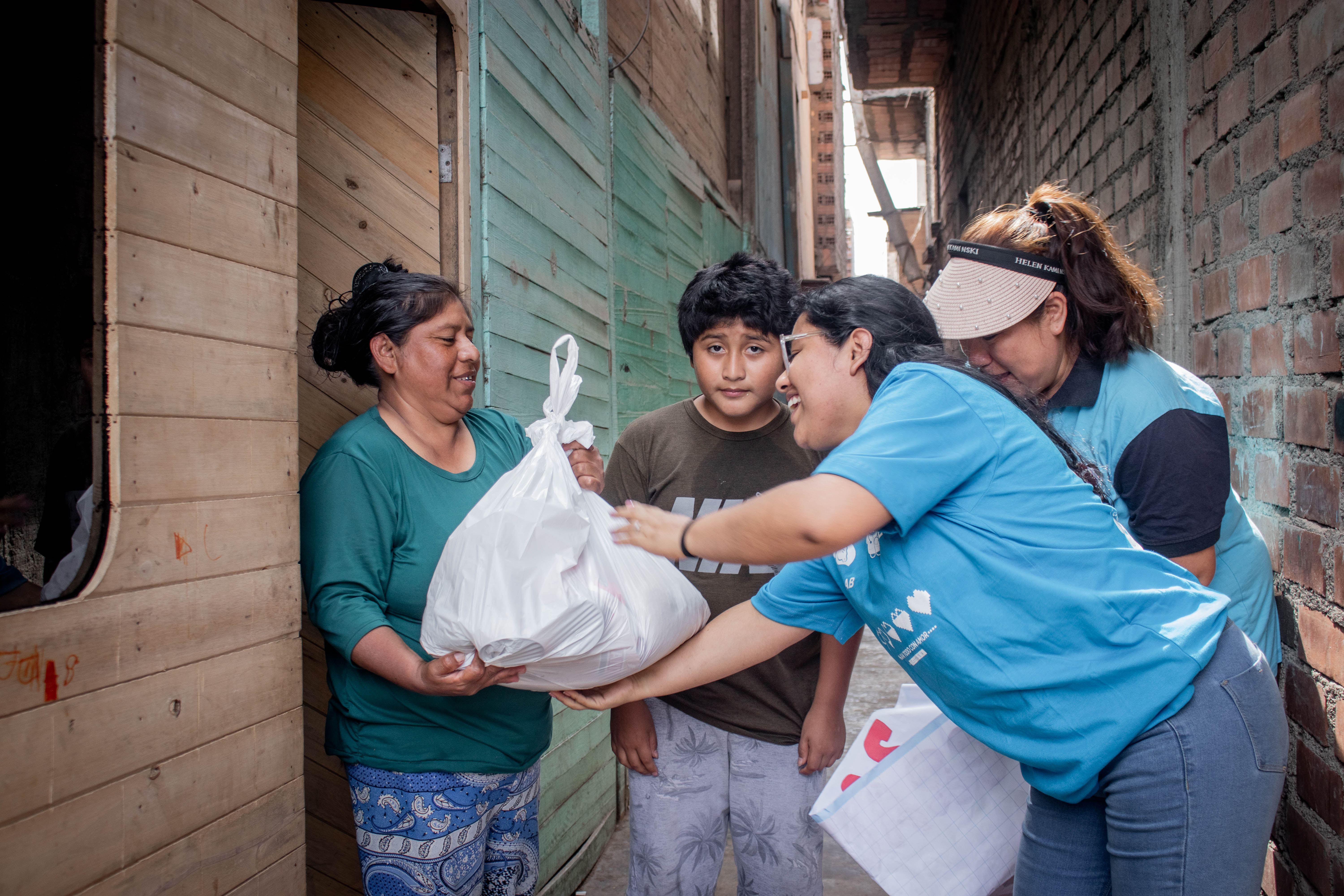 Volunteers handing food to family