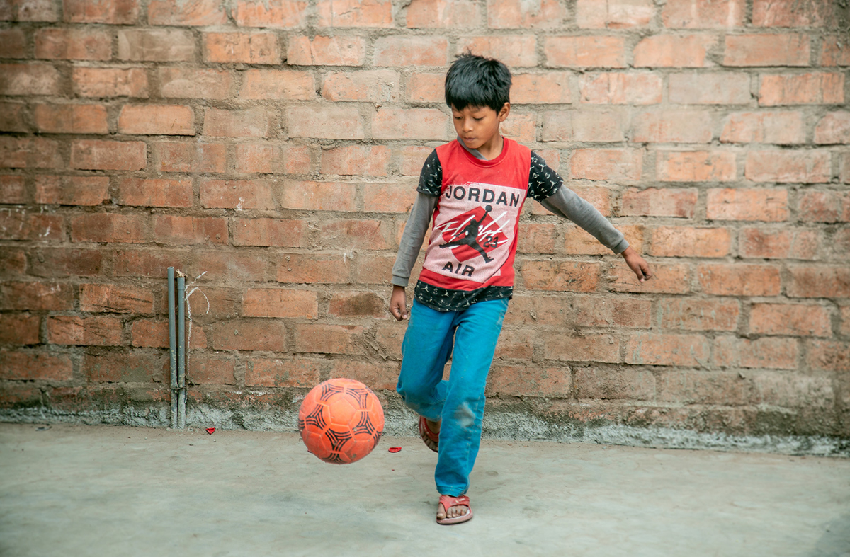 young boy kicking a oragne soccer ball