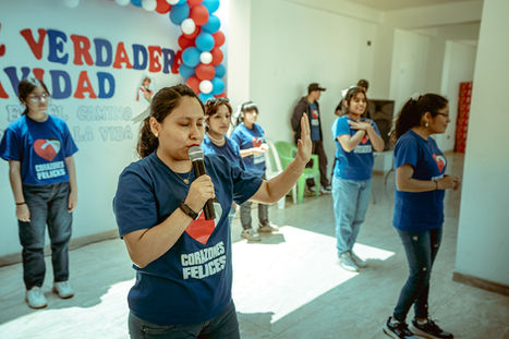 volunteer standing on a stage leading group of people in prayer