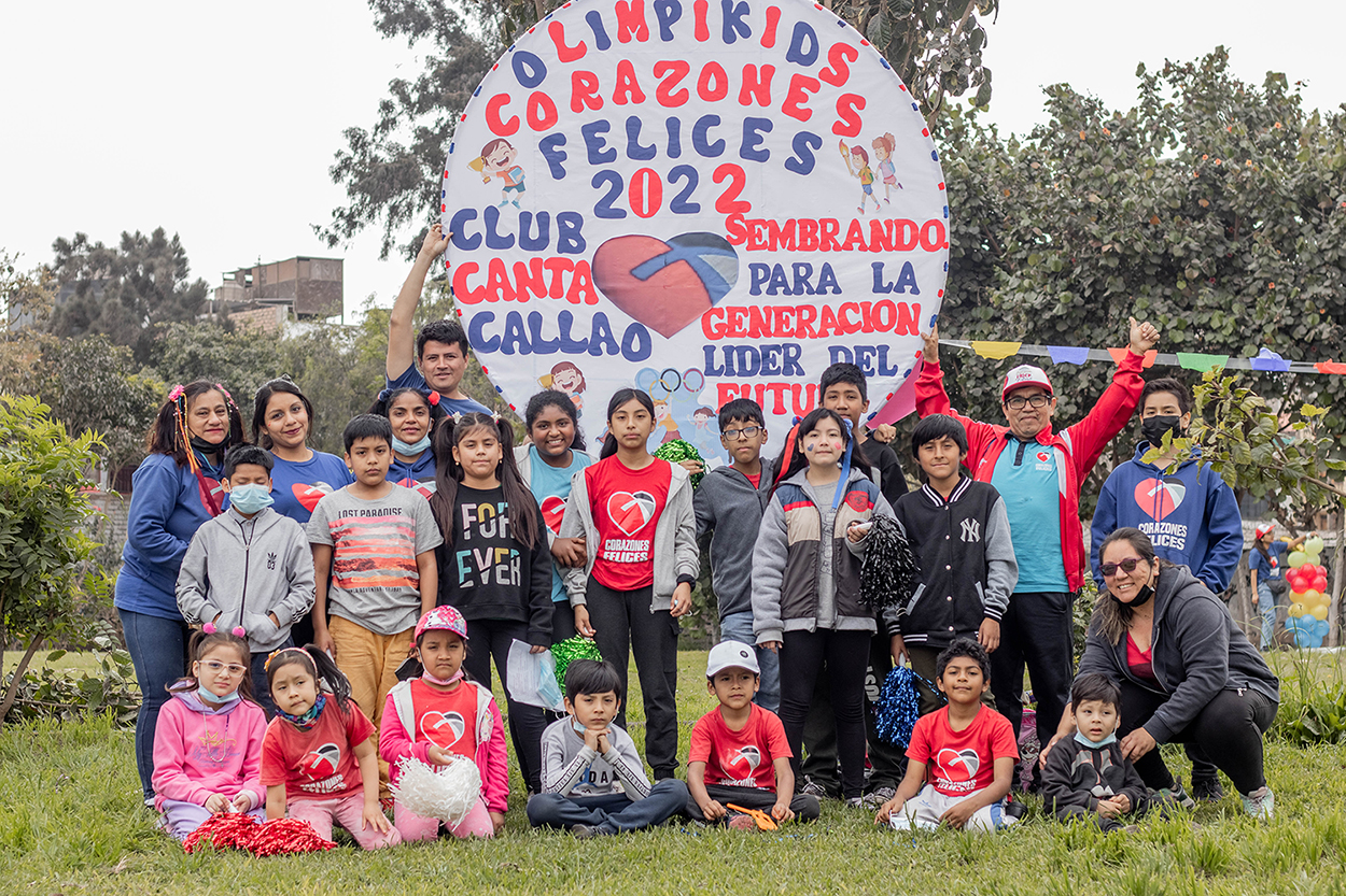 Group of kids standing in front of the olimpikids sign