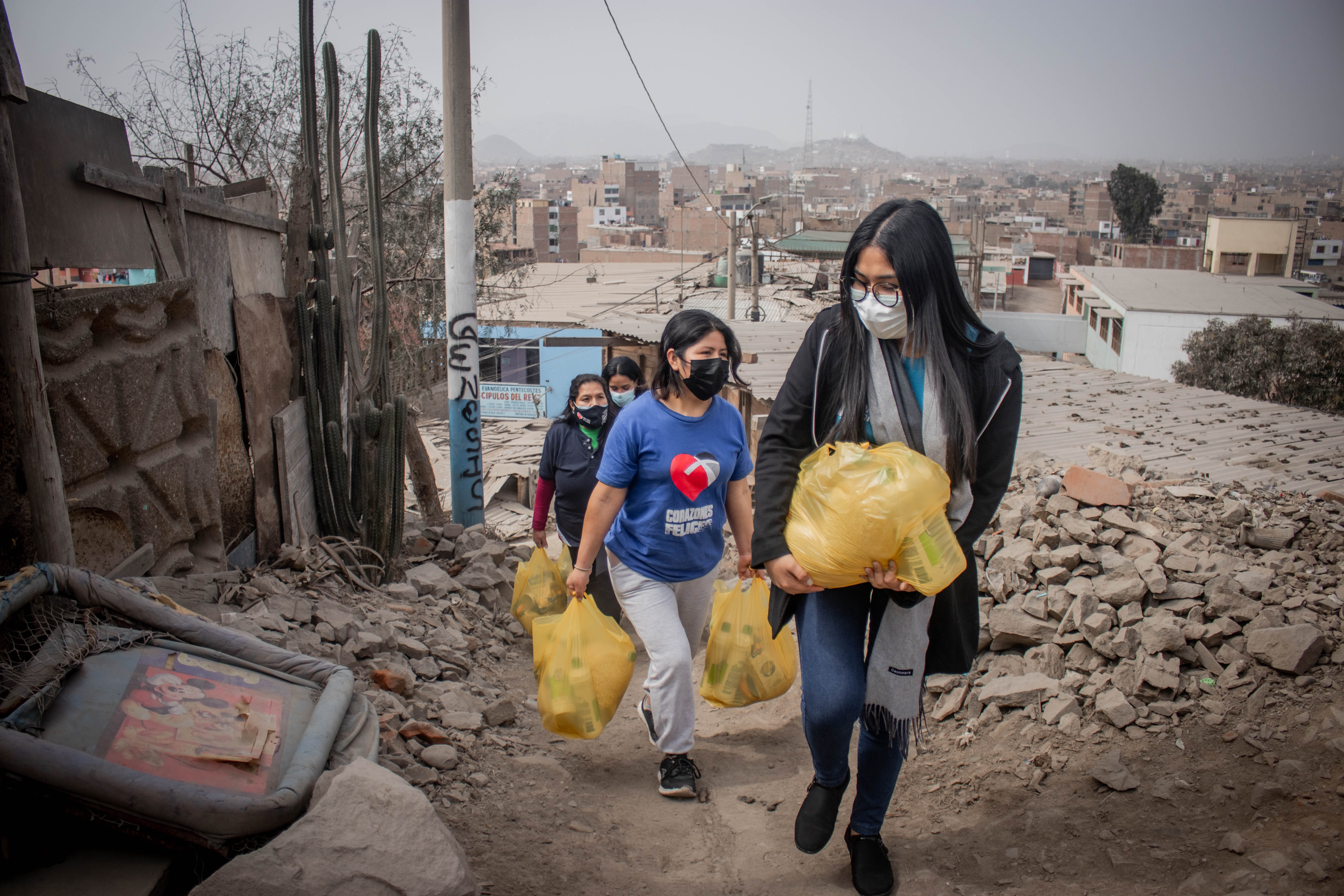 volunteers walking up a dirt path with yellow plastic bags