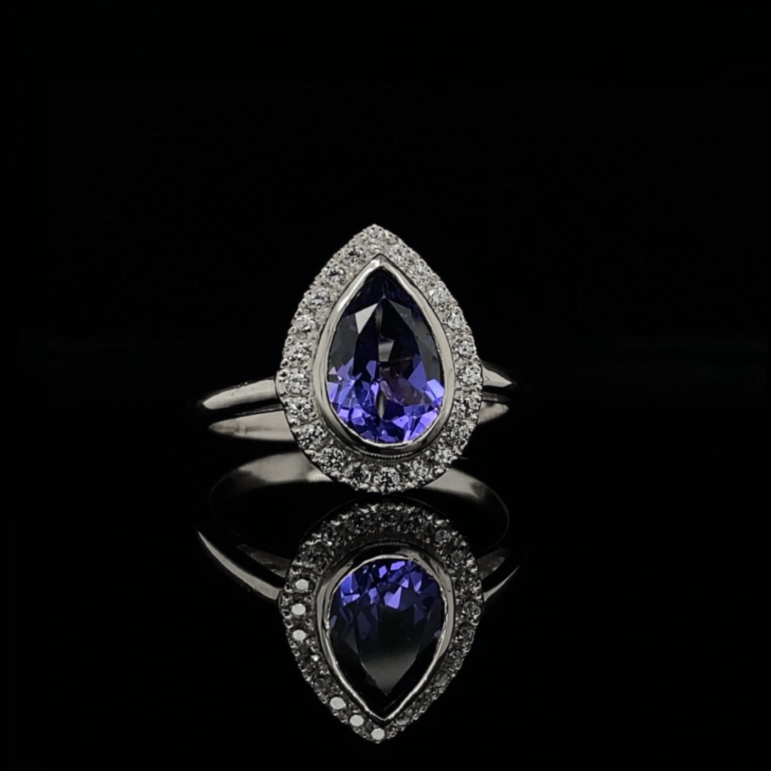 Pear Cut Tanzanite and Cubic Zirconia Bezel Halo Engagement Ring in White Gold