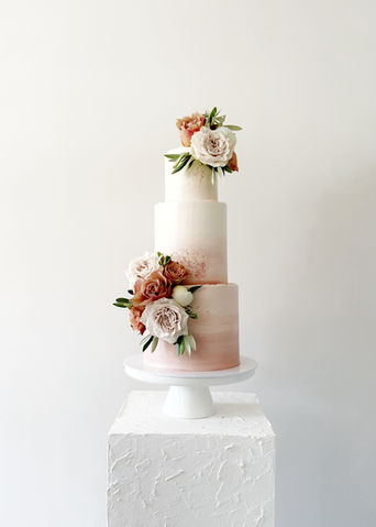 Een 3-laagse bruidstaart, afgewerkt met een botercrème in diverse oud roze tinten met ombre effect. Gedecoreerd met bloemen die overeenkwamen met de bloemen van het bruidsboeket en aankleding.
Nijverdal, Nederland, Overijssel, moderne bruidstaarten, bruiloft, sweet table, Mykitchenplayground