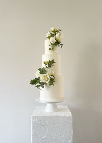 Een 3-laagse bruidstaart in een helder witte botercrème. Versierd met witte bloemen en veel groen die overeenkwamen met het bruidsboeket.
Nijverdal, Nederland, Overijssel, moderne bruidstaarten, bruiloft, sweet table, Mykitchenplayground