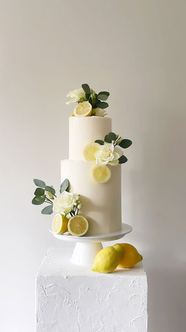 Een 2-laagse bruidstaart met een verhoogde onderste taart. Afgewerkt met een frisse witte botercrème en versierd met witte bloemen, groen en verse citroenen. Deze taart sloot helemaal aan bij de bruiloft met een Italiaans tintje.
Nijverdal, Nederland, Overijssel, moderne bruidstaarten, bruiloft, sweet table, Mykitchenplayground
