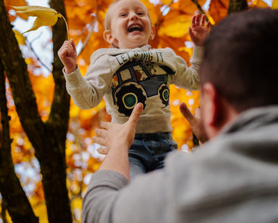Vater fotografiert lachendes Kind im Herbst