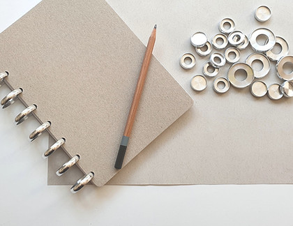 discbound notebook with a pencil next to different sized metal binding discs