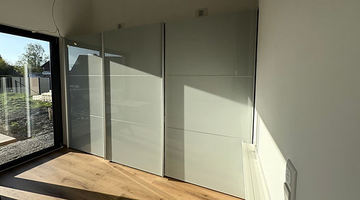 Heller Raum mit Holzfußboden, großem Fenster und Einbauschränken